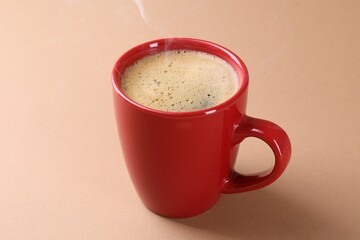 Aromatic coffee in cup on beige background, closeup