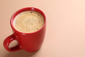 Aromatic coffee in cup on beige background, closeup. Space for text