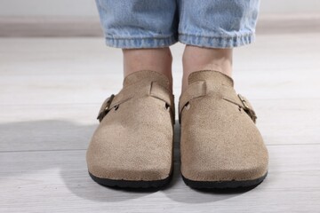 Woman in stylish beige slippers on light wooden floor, closeup