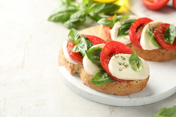 Delicious sandwiches with mozzarella cheese, tomatoes and basil on light grey table, closeup. Space for text
