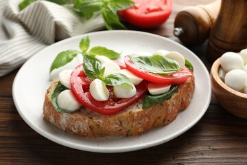 Delicious sandwich with mozzarella cheese, tomatoes and basil on wooden table, closeup