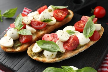 Delicious sandwiches with mozzarella cheese, tomatoes and basil on dark table, closeup