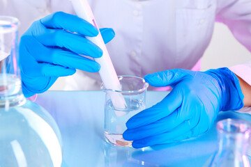 Fototapeta premium Scientist examining water with nitrate tester at white table in laboratory, closeup