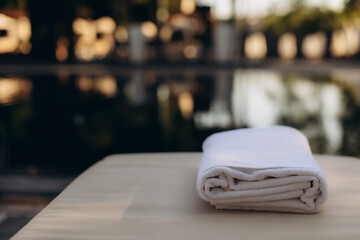 Folded white towel by the pool: relaxing vacation concept