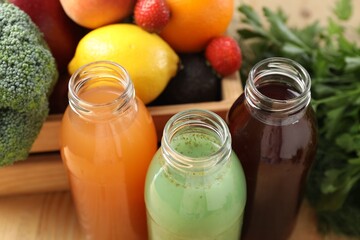 Tasty juices in glass bottles, fresh ingredients and herbs on wooden table, closeup