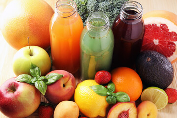 Tasty juices in glass bottles, fresh ingredients and basil on wooden table, closeup