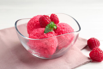 Delicious raspberry sorbet with mint in bowl, napkin and fresh berries on white wooden table, closeup