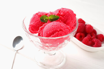 Delicious raspberry sorbet with mint in dessert bowl, spoon and fresh berries on white wooden table, closeup