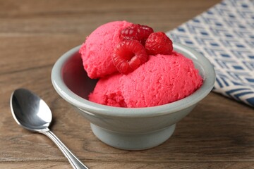 Delicious raspberry sorbet with fresh berries in bowl and spoon on wooden table, closeup