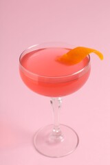 Martini cocktail with garnish on pink background, closeup