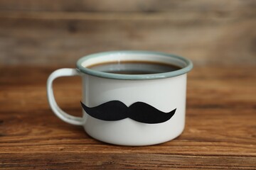Happy Father's Day. Cup with mustache on wooden table, closeup