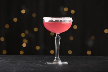 Martini cocktail with sugar in glass on black table against blurred lights, closeup