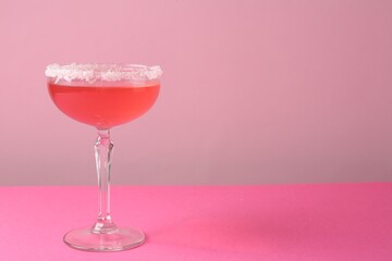 Martini cocktail with sugar in glass on pink background, closeup. Space for text