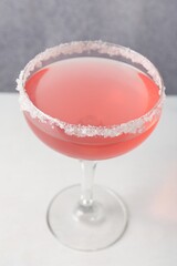 Martini cocktail with sugar in glass on white table near grey wall, closeup