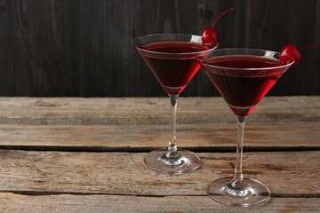 Martini cocktail with cherries in glasses on wooden table, closeup. Space for text