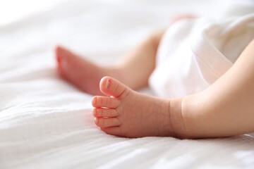 Cute newborn baby lying on bed indoors, closeup. Space for text