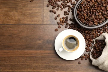 Fotobehang Koffiebar Aromatic coffee in cup and beans on wooden table, flat lay. Space for text  © New Africa