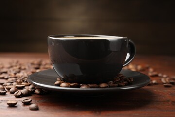 Aromatic coffee in cup and beans on wooden table, closeup