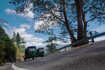 A green truck is driving down a curvy road in Sri Lanka, passing through lush landscapes.