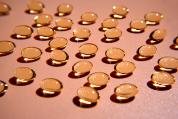 Golden vitamin pills casting shadows on pink background
