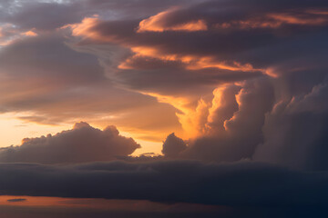 Ominous, billowing clouds in dramatic lighting fill the sky, with dark grays contrasted by edges of orange and gold