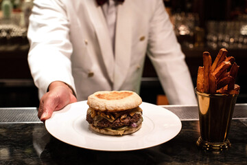 Bartender serving a hamburger on a plate