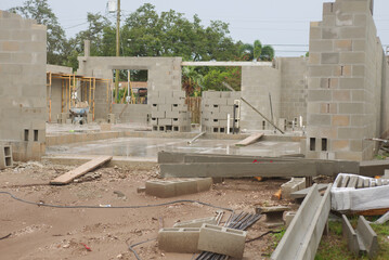 Partially Constructed Cement Block Building Foundation on a Cloudy Day. Incomplete construction site with cement block walls and open interiors, giving a sense of progress.
