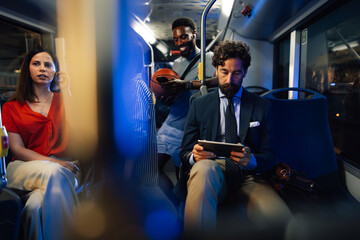 Multiethnic passengers using digital devices while riding bus