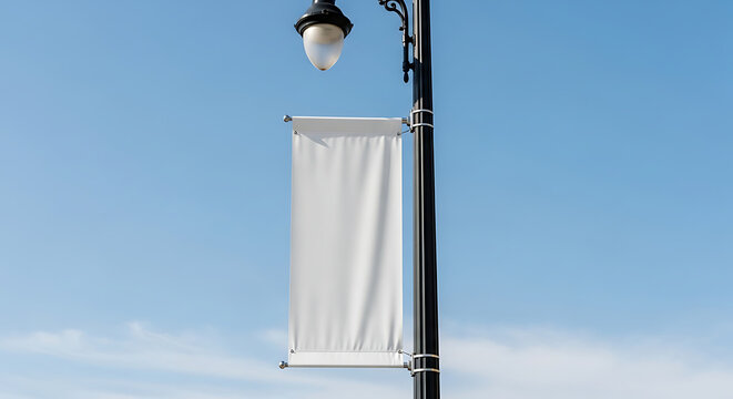 Blank banner hangs on light pole against blue sky. Blank banner for advertising, promotions, and city announcements captures attention. Perfect blank banner for events, festivals, and local marketing.