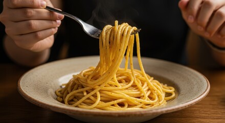 Close up of a fork twirling a generous portion of golden spaghetti noodles from a rustic bowl