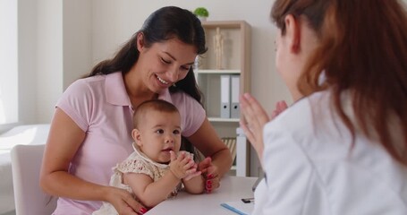 Mother and baby visit a pediatrician for consultation at a clinic, discussing healthcare, appointment notes, and the upcoming checkup for the child. Doctor greets mother and baby warmly.