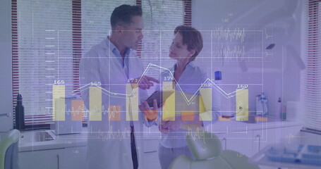 Reviewing tablet, dentist and colleague in lab coat and blouse in dental clinic, with green chair