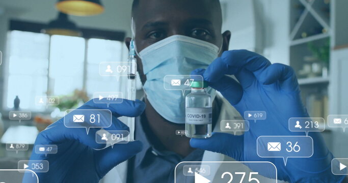 Holding masked researcher inspecting COVID-19 vaccine vial in laboratory, with notification icons