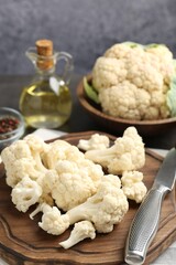 Fresh raw cauliflower florets, spices and knife on table, closeup