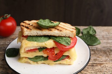 Delicious sandwiches with melted cheese, spinach and tomatoes on wooden table, closeup
