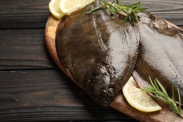 Fresh flounder fish, lemon and rosemary on wooden table, closeup. Raw seafood