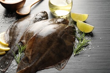 Fresh flounder fish, salt and products on black wooden table, closeup. Raw seafood