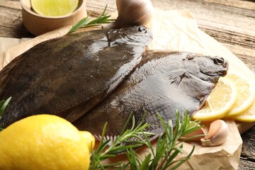 Fresh flounder fish, lemon, rosemary and garlic on wooden table, closeup. Raw seafood