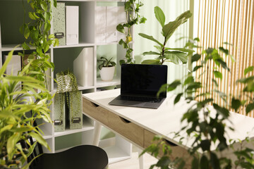 Biophilic interior design. Stylish workplace with laptop and houseplants in office