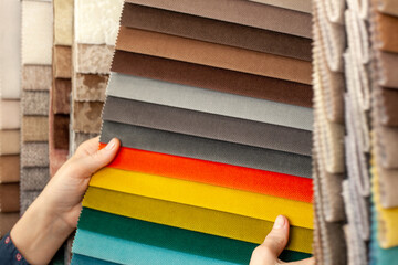 Samples of multicolored fabrics. A woman chooses a fabric for a sofa. Catalog of textiles for the...