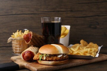Different delicious fast food and cola on wooden table, closeup