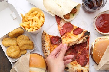 Woman taking piece of pizza at table, top view