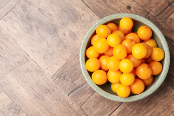 Ripe yellow cherry plums on wooden table, top view. Space for text