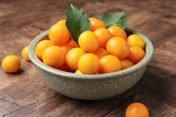 Ripe yellow cherry plums and leaves on wooden table, closeup