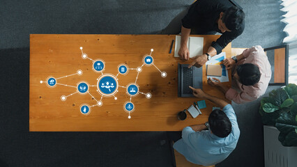 Aerial view of a diverse business team collaborating on technology solutions, surrounded by networking icons, highlighting teamwork and digital innovation in a modern workspace. Amity