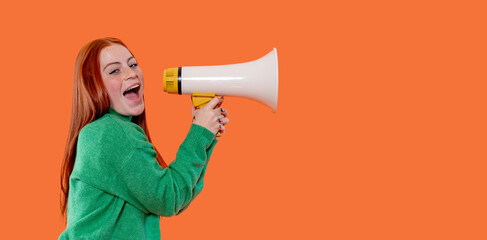 Young woman energetically shouting into a megaphone against a bright orange background during a spirited event or campaign