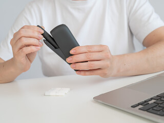 A woman takes a tobacco heating system out of a charger. Electronic cigarette.