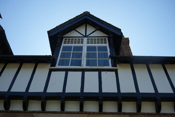 Dale Abbey, Derbyshire, England – August 25 2025: Tudor style timber framed upper window with blue sky in Dale Abbey, Derbyshire, England on a sunny day.