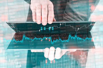 Person holds a modern laptop in hands with a prominent digital financial chart and market data overlaid on the screen. Concept of online trading, investment analysis and digital technology.