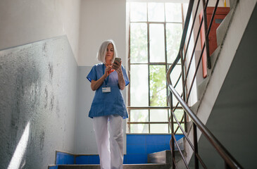 Tired nurse taking break during hospital shift, texting with family.